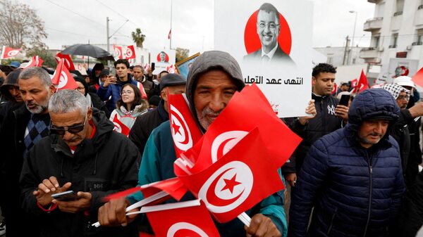 A man holds Tunisian national flags during a protest against Tunisian President Kais Saied's seizure of governing powers, in Tunis, Tunisia March 20, 2022. - Sputnik International