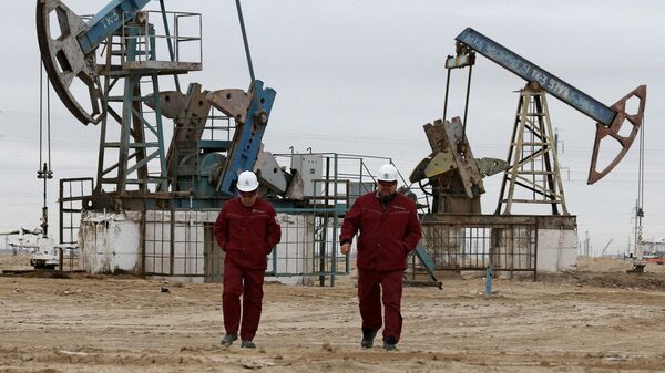 Workers walk as oil pumps are seen in the background in the Uzen oil and gas field in the Mangistau Region of Kazakhstan November 13, 2021. - Sputnik International