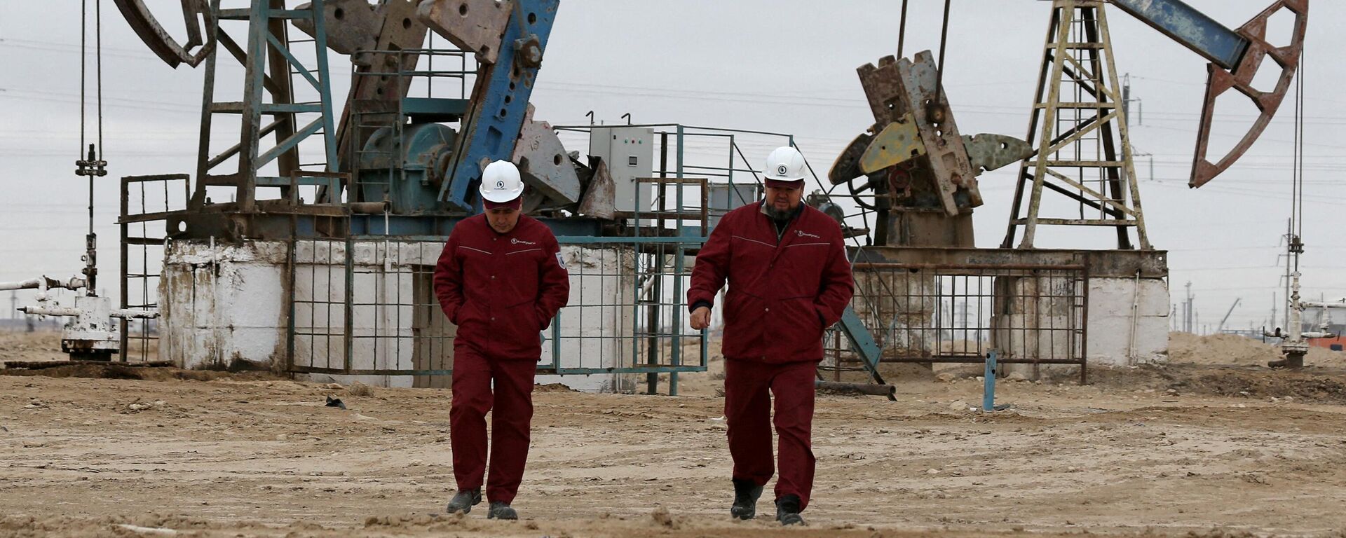 Workers walk as oil pumps are seen in the background in the Uzen oil and gas field in the Mangistau Region of Kazakhstan November 13, 2021. - Sputnik International, 1920, 30.03.2022