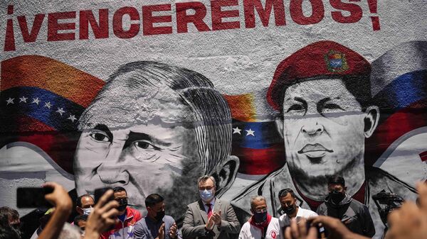 Russian Ambassador to Venezuela, Sergey Melik Bagdasarov, center, stands in front of a mural featuring Russian President Vladimir Putin and the late President Hugo Chavez, during an event to inaugurate a basketball and soccer venue, in the Catia neighborhood of Caracas, Venezuela, Saturday, April 2, 2022.  - Sputnik International