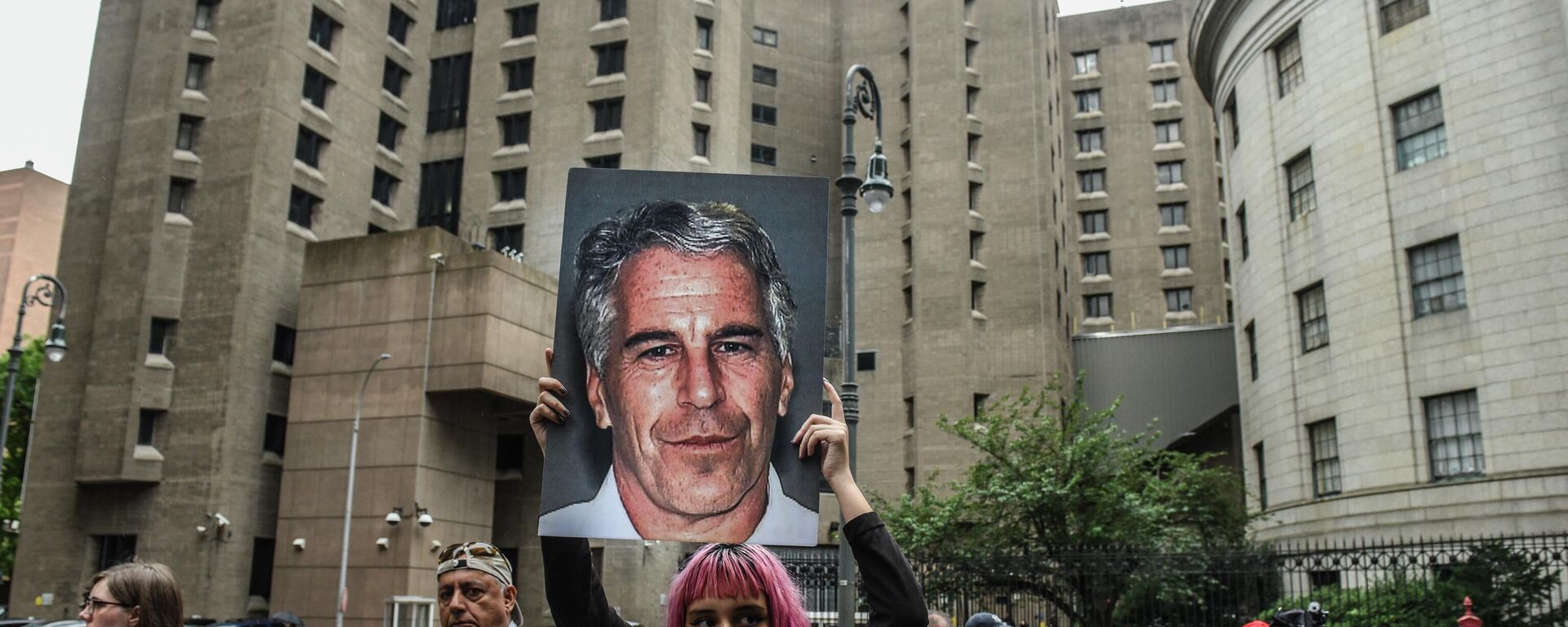 A member of a protest group called Hot Mess holds up a sign of Jeffrey Epstein in front of the Metropolitan Correction Center on July 8, 2019 in New York City. - Sputnik International, 1920, 05.04.2022