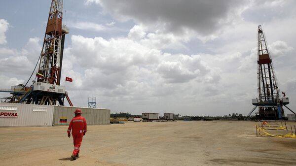 An oilfield worker walks next to drilling rigs at an oil well operated by Venezuela's state oil company PDVSA, in the oil-rich Orinoco belt, April 16, 2015. - Sputnik International