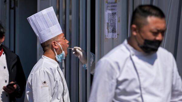 A restaurant chef gets their throat swab taken at a coronavirus testing site, Sunday, April 3, 2022, in Beijing. COVID-19 cases in China's largest city of Shanghai are still rising as millions remain isolated at home under a sweeping lockdown. - Sputnik International