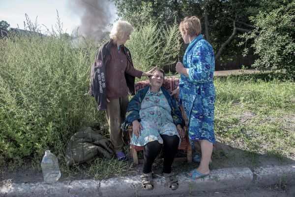 Aftermath of the shelling of Slavyansk by the Ukrainian Armed Forces. Neighbours help a woman whose house caught on fire due to a shell hitting it. - Sputnik International