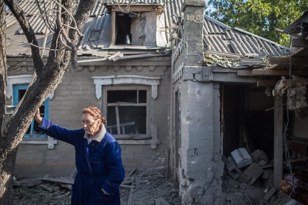 August 2015: Woman stands near her home, which has been damaged in Ukrainian strikes, in Alexandrovka. - Sputnik International