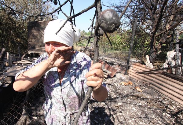 July 2019: A woman weeps near her apple tree, destroyed in a blaze along with her home in shelling by Ukrainian forces. - Sputnik International