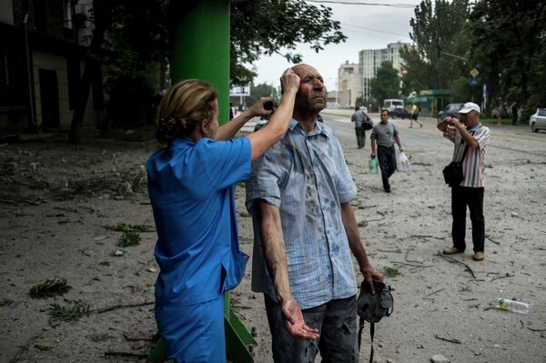 After shelling attacks, doctors and nurses would take to the streets to provide emergency medical assistance.Above: A doctor assists a victim of an artillery strike in Lugansk. - Sputnik International