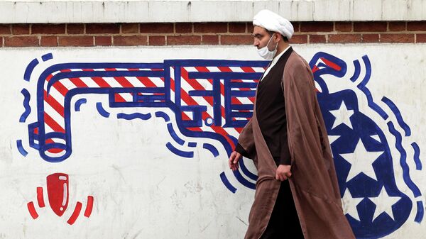 An Iranian cleric walks past an anti-US mural on a wall of the former United States embassy in the capital Tehran, on March 12, 2022. - Sputnik International