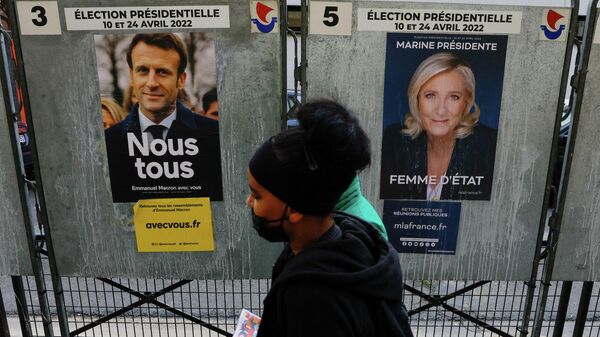 People walk past official campaign posters of French presidential election candidates Marine le Pen, leader of French right-wing National Rally (Rassemblement National) party, and French President Emmanuel Macron, candidate for his re-election, displayed on bulletin boards in Paris, France,  - Sputnik International