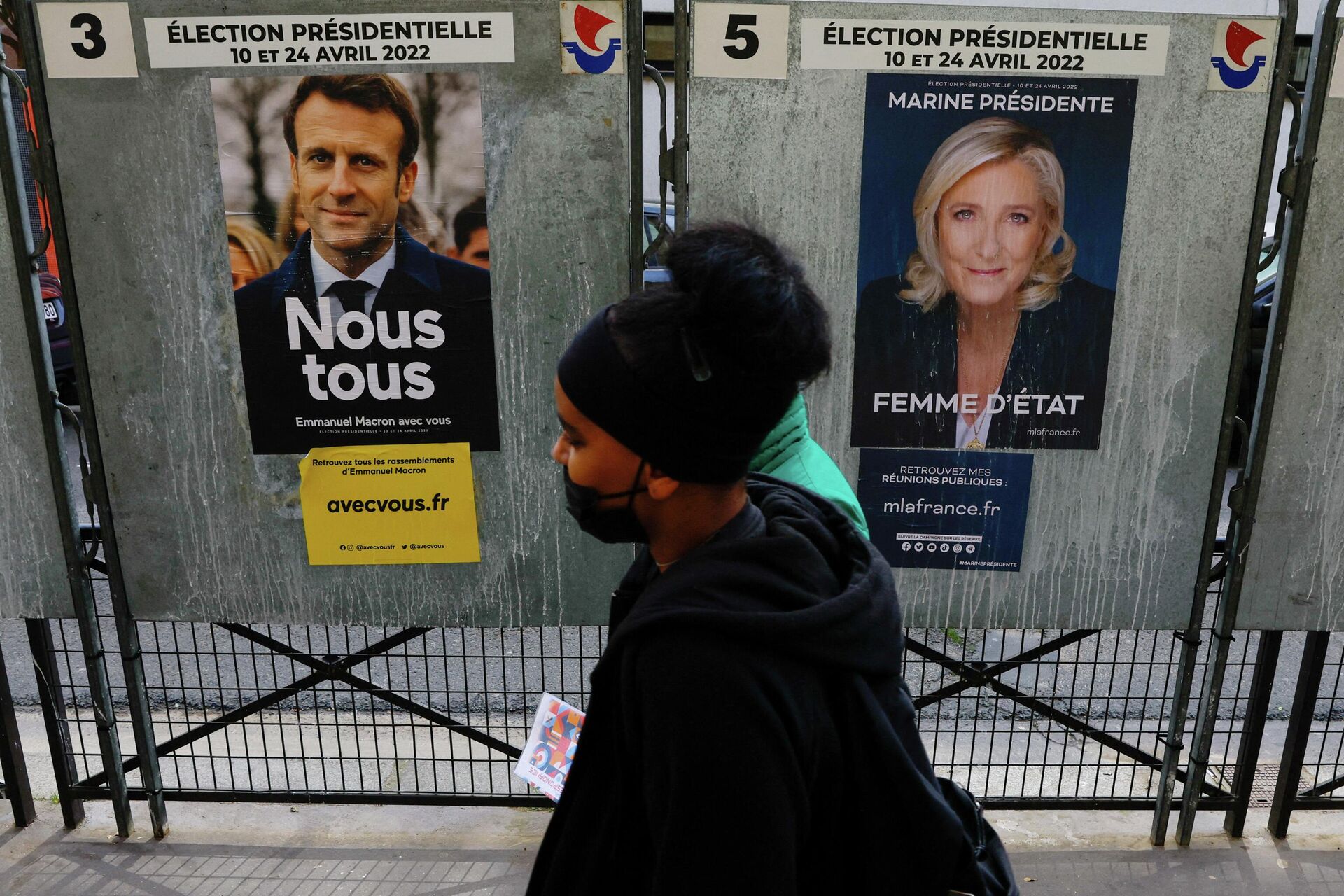 People walk past official campaign posters of French presidential election candidates Marine le Pen, leader of French right-wing National Rally (Rassemblement National) party, and French President Emmanuel Macron, candidate for his re-election, displayed on bulletin boards in Paris, France,  - Sputnik International, 1920, 19.04.2022