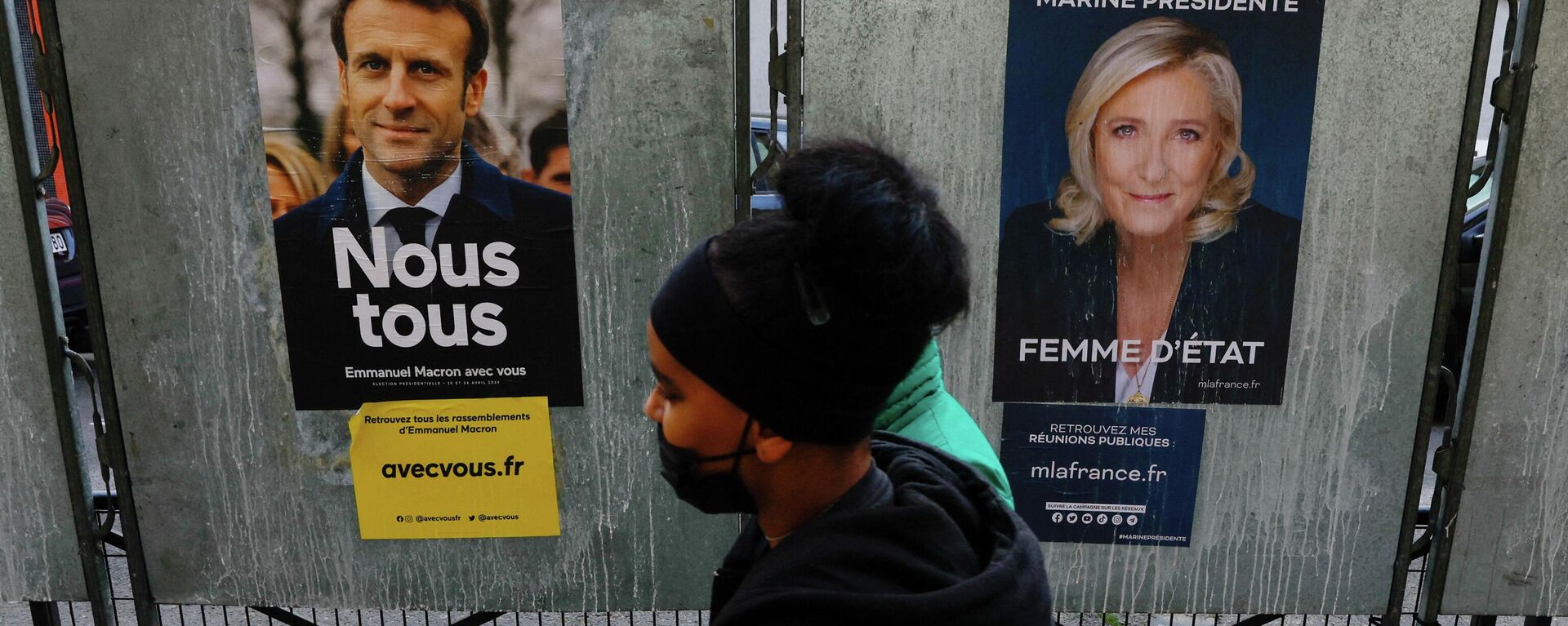 People walk past official campaign posters of French presidential election candidates Marine le Pen, leader of French right-wing National Rally (Rassemblement National) party, and French President Emmanuel Macron, candidate for his re-election, displayed on bulletin boards in Paris, France,  - Sputnik International, 1920, 22.04.2022