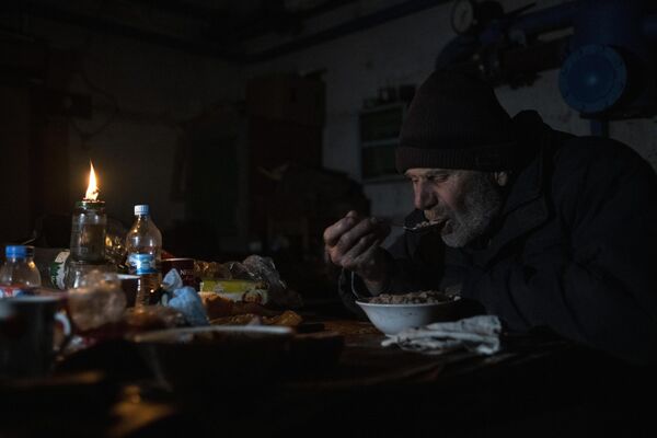 Elderly people had to sleep and eat in dark and cold cellars to survive the shelling of their homes. Photo: A man having dinner in the basement of a house in the city of Rubezhnoye, Lugansk region. - Sputnik International