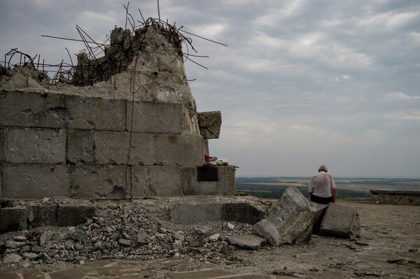 An elderly man sits beside the Saur-Grave monument in the Donetsk region, destroyed in fighting between the Donbass People&#x27;s Militia and Ukrainian Armed Forces. This monument honours the liberation of Donbass from the Nazis. Fierce battles took place for this strategic height during World War II. In 2014, everything happened again. - Sputnik International