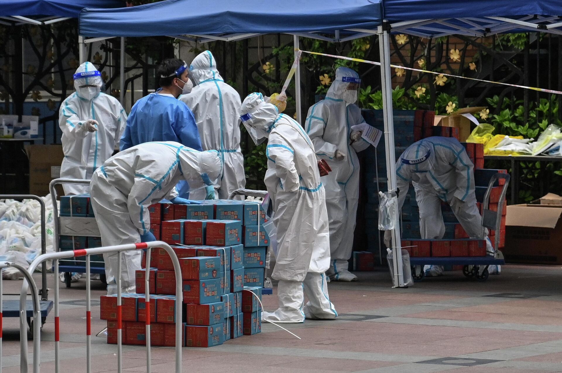 Workers wearing personal protective equipment (PPE) are seen next to food delivered by the local government for residents in a compound during a Covid-19 lockdown in the Jing'an district in Shanghai on April 10, 2022.  - Sputnik International, 1920, 11.05.2022