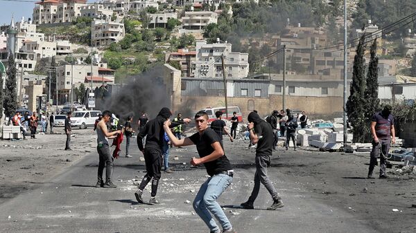 Palestinian protesters hurl rocks at Israeli security amid clashes during a demonstration against Jewish settlements and in support of Jerusalem's Al-Aqsa mosque, on the main street of Beita village in the occupied West Bank, on April 15, 2022. - Sputnik International