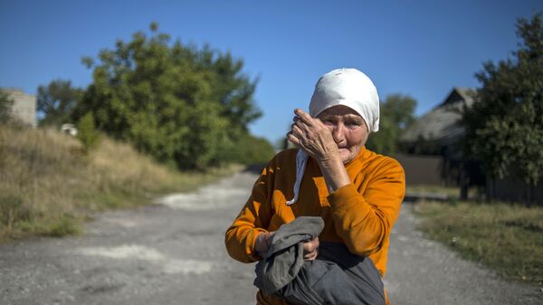 A woman wipes away tears near a convoy of vehicles from the 38th Russian humanitarian convoy to Donetsk in September 2015. For many residents of Donbass, humanitarian aid convoys consisting of food, medicines, and basic hygiene products became critical to survival.  - Sputnik International