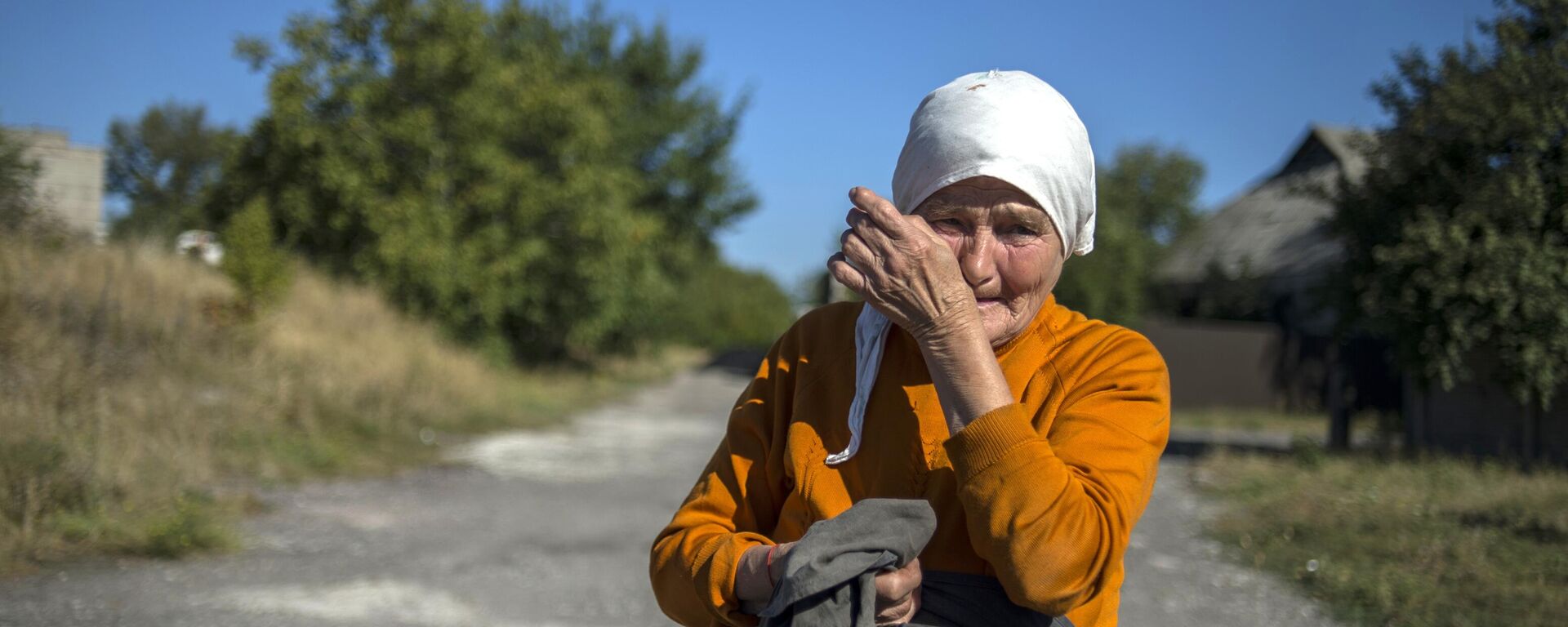 A woman wipes away tears near a convoy of vehicles from the 38th Russian humanitarian convoy to Donetsk in September 2015. For many residents of Donbass, humanitarian aid convoys consisting of food, medicines, and basic hygiene products became critical to survival.  - Sputnik International, 1920, 31.03.2024