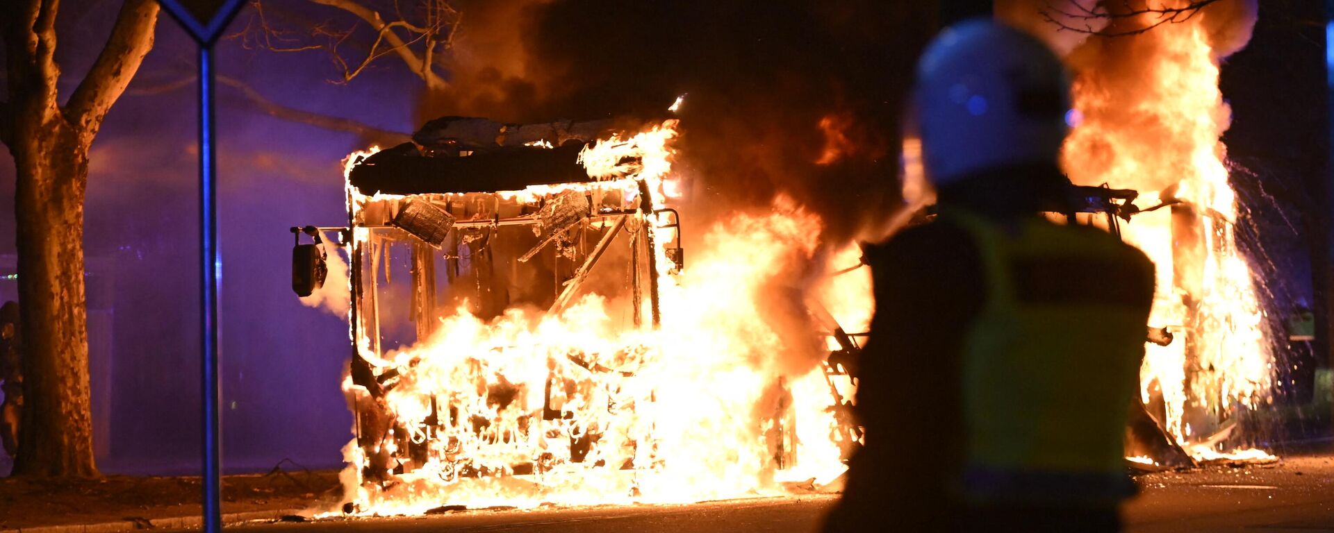 An anti-riot police officer stands next to a city bus burning in Malmo late April 16, 2022 - Sputnik International, 1920, 17.04.2022