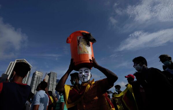 Мужчина несет мусорное ведро с наклеенным на него портретом президента Готабайи Раджапаксы во время антиправительственной акции в Коломбо,  Шри-Ланка - Sputnik International