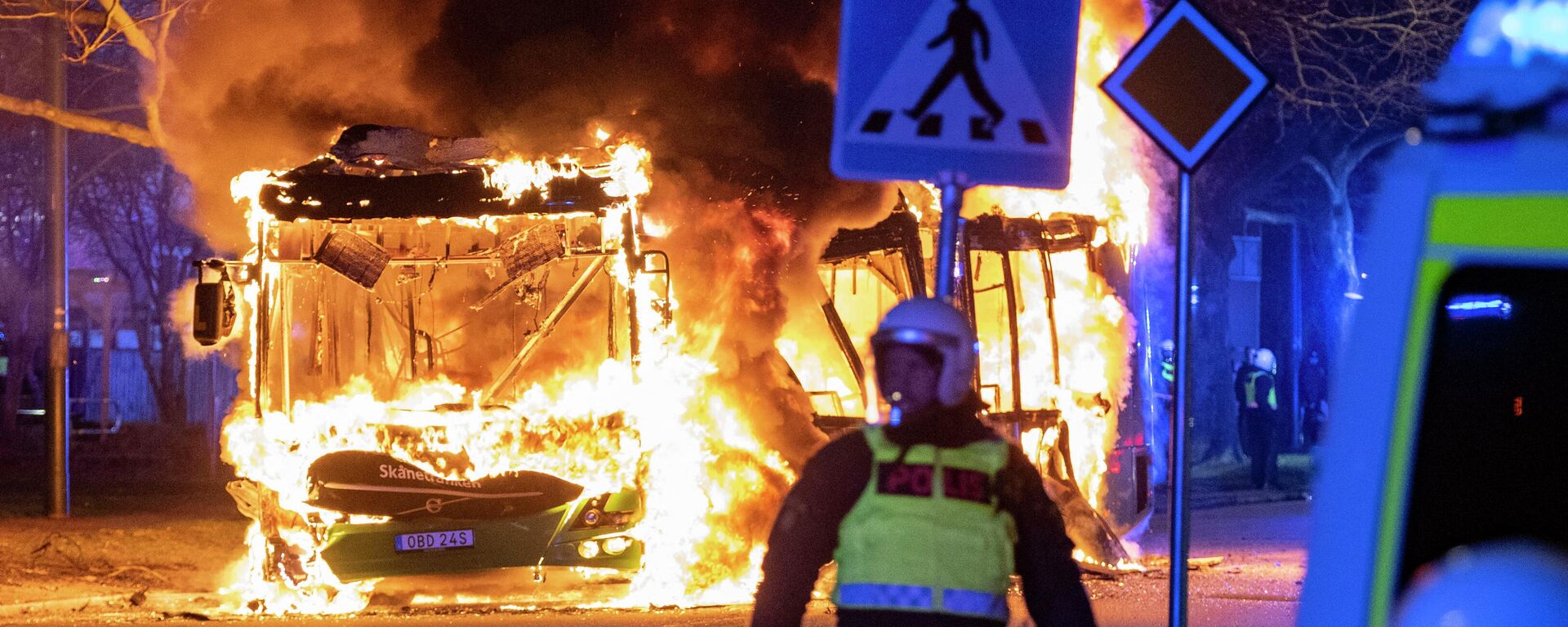 An anti-riot police officer stands next to a city bus burning in Malmo late April 16, 2022. - The unrest in Malmo has continued after Rasmus Paludan, party leader of the Danish right-wing extremist party Tight Course, held a demonstration on April 16, 2022 at Skanegarden near the Oresund Bridge. (Photo by Johan NILSSON / TT NEWS AGENCY / AFP)  - Sputnik International, 1920, 02.05.2022