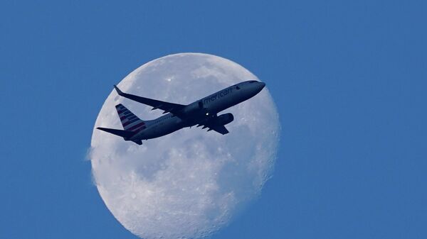 An American Airlines Boeing 737 flies past the moon as it heads to Orlando, Fla., after having taken off from Miami International Airport, Tuesday, April 19, 2022, in Miami. The major airlines and many of the busiest airports rushed to drop their requirements on Monday after a Florida judge struck down the CDC mandate and the Transportation Security Administration announced it wouldn't enforce its 2021 security directive.  - Sputnik International