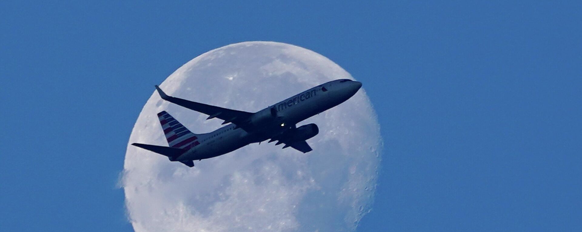 An American Airlines Boeing 737 flies past the moon as it heads to Orlando, Fla., after having taken off from Miami International Airport, Tuesday, April 19, 2022, in Miami. The major airlines and many of the busiest airports rushed to drop their requirements on Monday after a Florida judge struck down the CDC mandate and the Transportation Security Administration announced it wouldn't enforce its 2021 security directive.  - Sputnik International, 1920, 12.03.2024