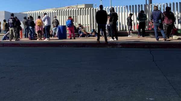 Migrants waiting to cross into the United States wait for news at the border crossing Wednesday, Feb. 17, 2021, in Tijuana, Mexico.   - Sputnik International