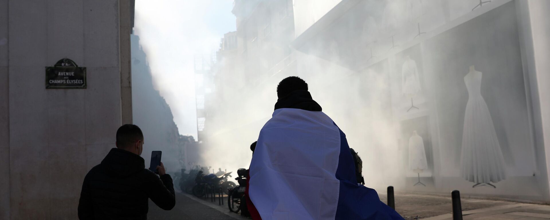 A protester leaves the Champs-Elysees avenue though tear gas during a protest, Saturday, Feb.12, 2022 in Paris. - Sputnik International, 1920, 24.04.2022