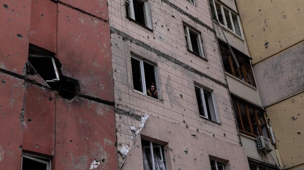 A woman looks out of a building damaged by shelling last month, in Irpin, on the outskirts of Kiev, on Thursday, April 21, 2022. - Sputnik International