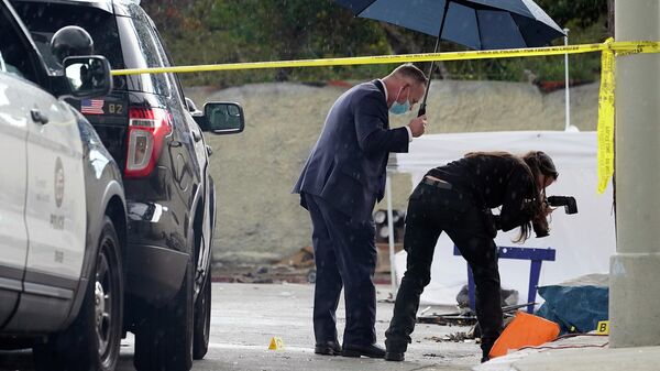 A Los Angeles Police investigator takes pictures in the rain, as investigators gather evidence in the death of an adult male found dead at a homeless encampment in downtown Los Angeles on March 12, 2021. - Sputnik International