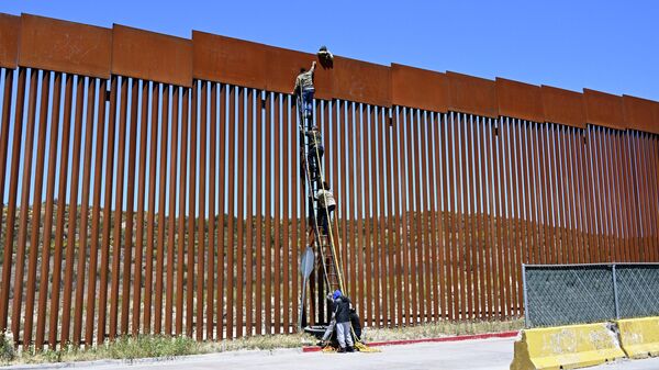 People use a ladder to scale the border fence at the US/Mexico border in Tecate, Mexico, Thursday, April 21, 2022. - Sputnik International