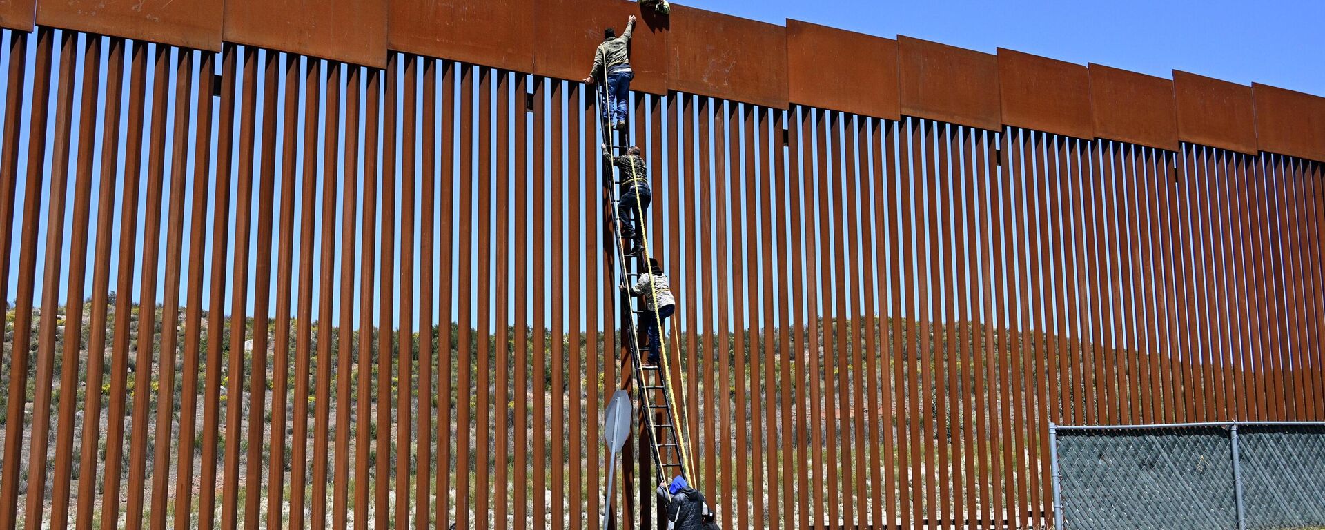 People use a ladder to scale the border fence at the US/Mexico border in Tecate, Mexico, Thursday, April 21, 2022. - Sputnik International, 1920, 25.04.2022
