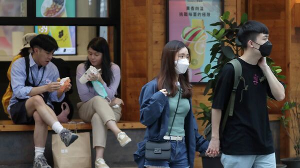 People wearing face masks to protect against the spread of the coronavirus walk on a street in Taipei, Taiwan, Saturday, April 30, 2022. - Sputnik International