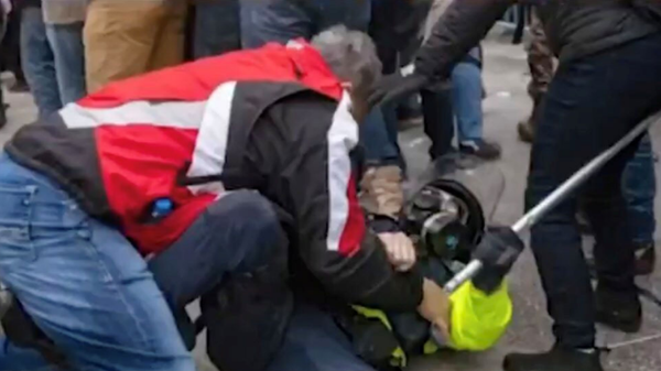 A still from a video included in a US Department of Justice complaint showing New York Police Department (NYPD) officer Thomas Webster on top of Metropolitan Police Department (MPD) officer Noah Rathbun, attempting to remove his gas mask during a confrontation in the US Capitol Insurrection on January 6, 2021. - Sputnik International