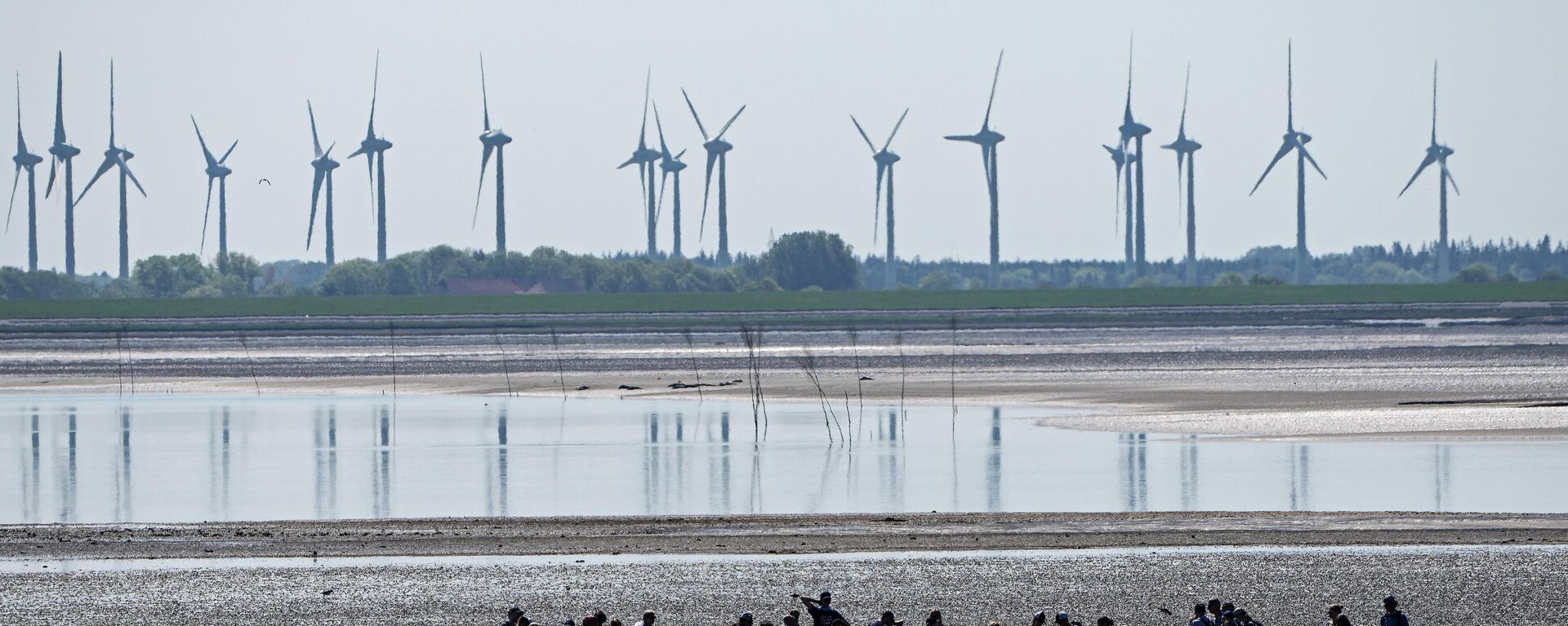 In this June 1, 2021 file photo, people explore the wadden sea at the island Norderney, Germany, in front of wind turbines, producing renewable energy. - Sputnik International, 1920, 02.05.2022