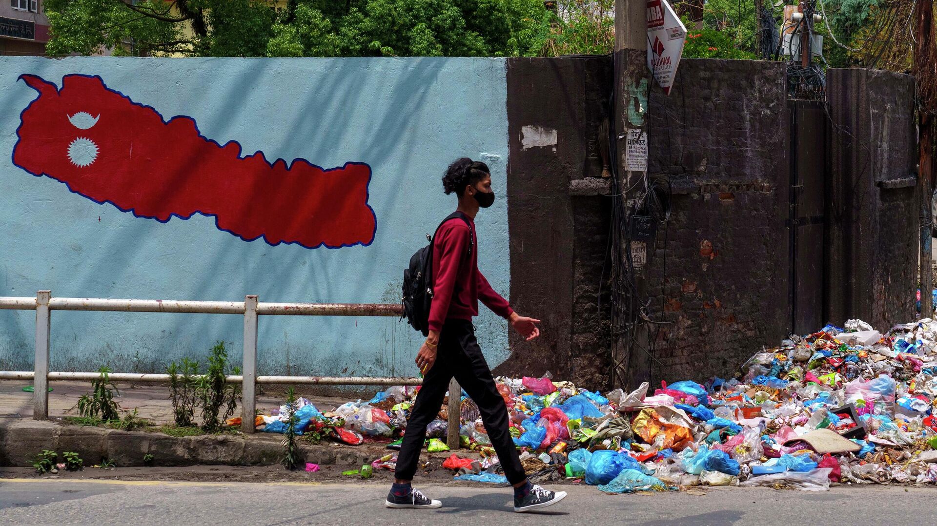 A Nepalese walks in front of wall painting of a map of Nepal next to the garbage in Kathmandu, Nepal, Tuesday, May 3, 2022 - Sputnik International, 1920, 04.05.2022