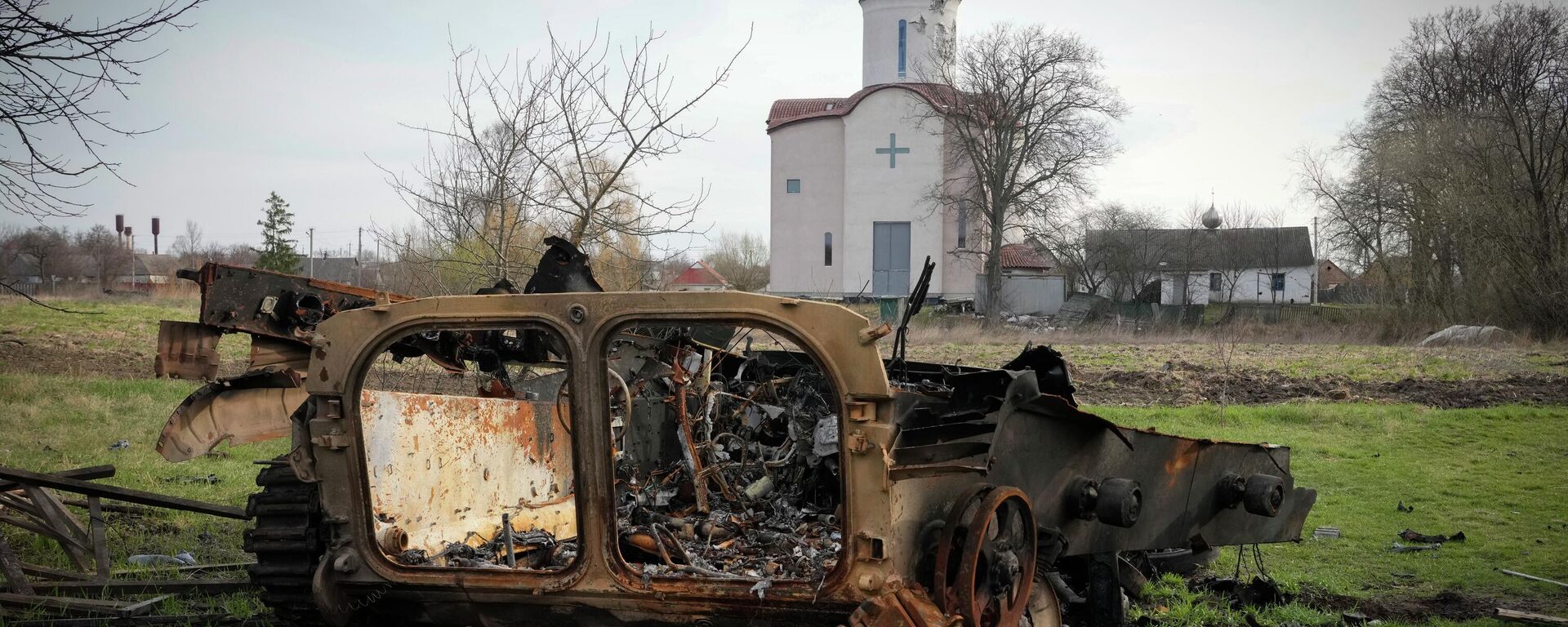 Fragments of a destroyed Russian military vehicle lie against the background of an Orthodox church in the village of Lypivka close to Kiev, Ukraine, on April 11, 2022.  - Sputnik International, 1920, 15.05.2022
