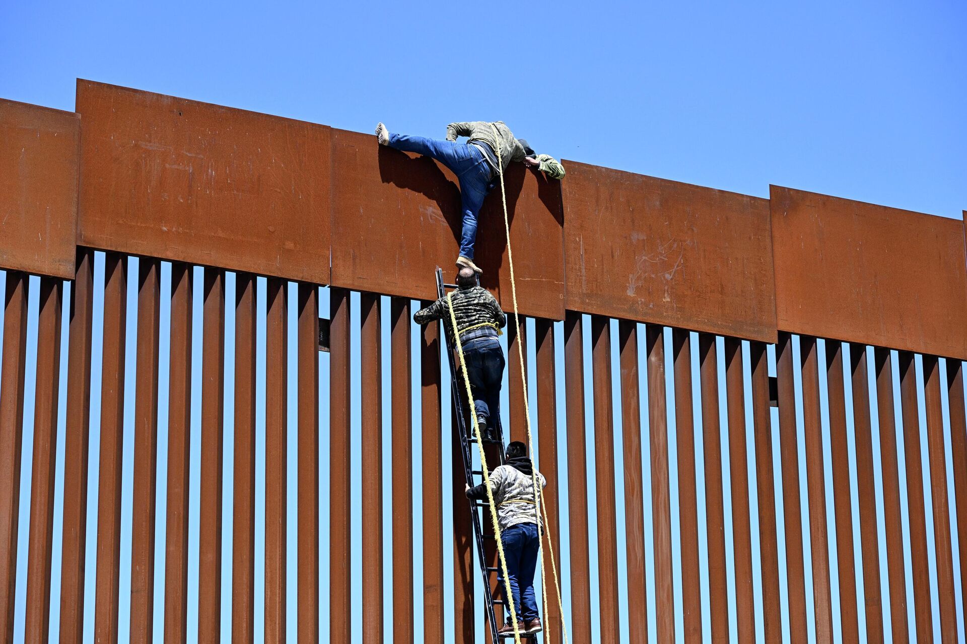 People use a ladder to scale the border fence at the US/Mexico border in Tecate, Mexico, Thursday, April 21, 2022. The men used the ropes to lower themselves down on the United States side. - Sputnik International, 1920, 16.09.2022