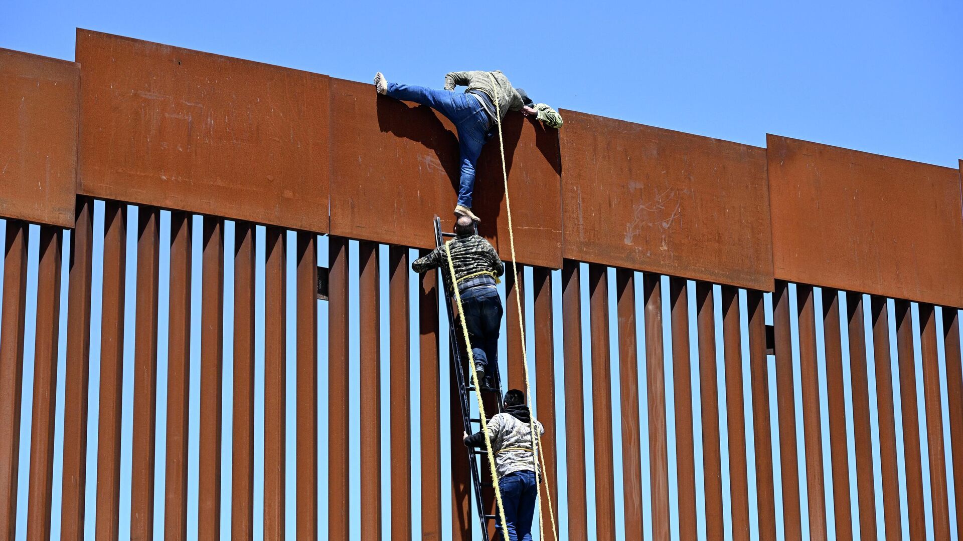 People use a ladder to scale the border fence at the US/Mexico border in Tecate, Mexico, Thursday, April 21, 2022. The men used the ropes to lower themselves down on the United States side. - Sputnik International, 1920, 06.05.2022