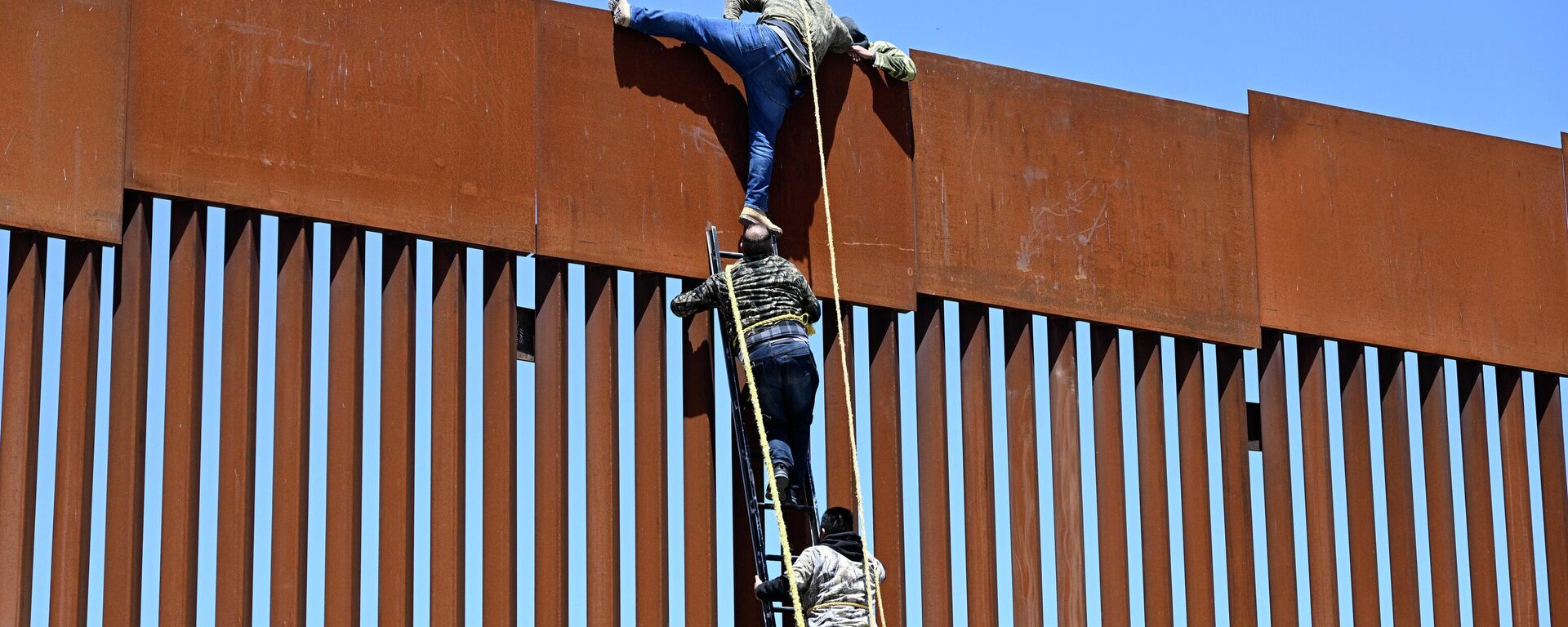 People use a ladder to scale the border fence at the US/Mexico border in Tecate, Mexico, Thursday, April 21, 2022. The men used the ropes to lower themselves down on the United States side. - Sputnik International, 1920, 12.05.2022