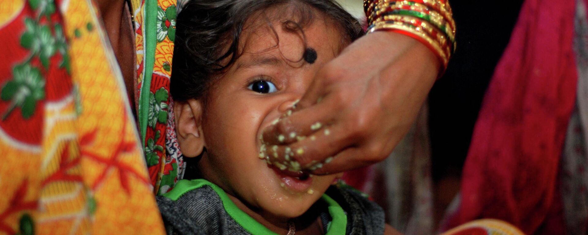 A mother feeds her child as Indian volunteers distribute relief food to cyclone evacuated people in a relief camp at Chatrapur, about 180 kilometers south of eastern city Bhubaneswar on October 12, 2013 - Sputnik International, 1920, 11.05.2022