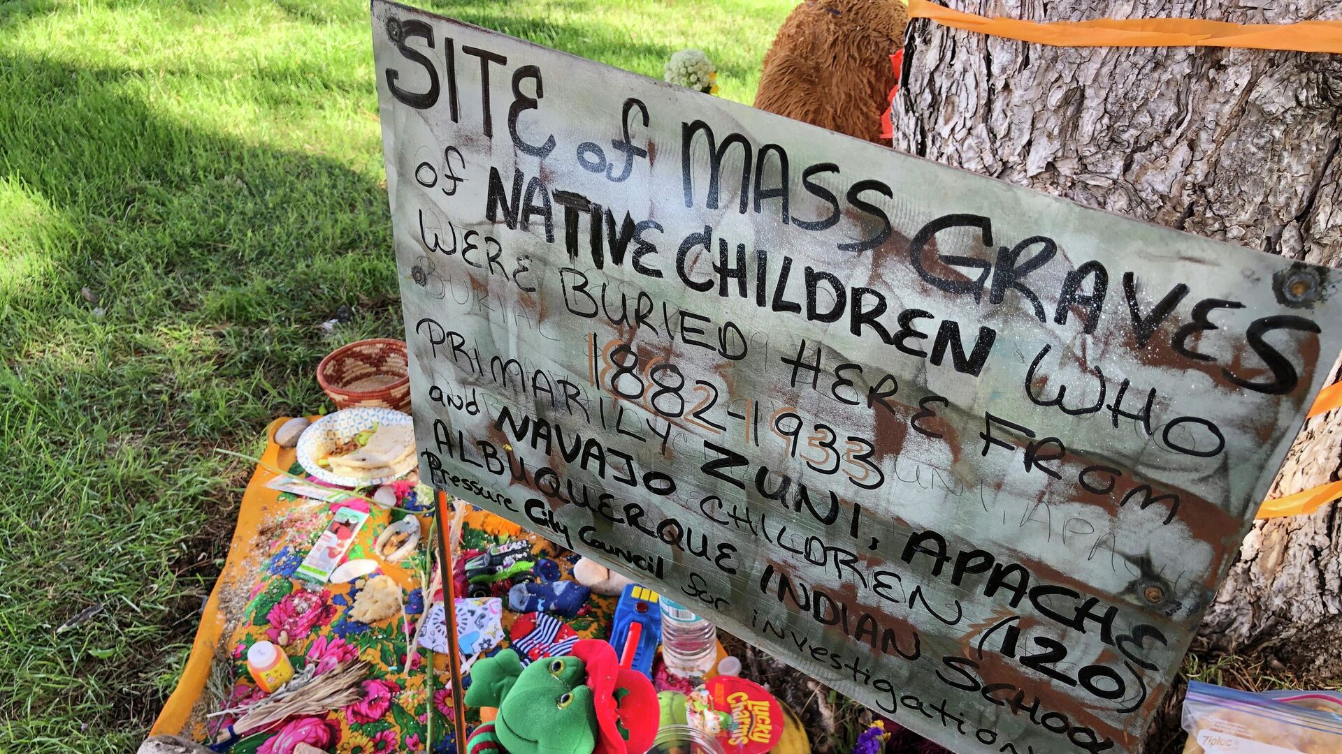 A makeshift memorial for the dozens of Indigenous children who died more than a century ago while attending a boarding school that was once located nearby is displayed under a tree at a public park in Albuquerque, N.M., on  July 1, 2021.  - Sputnik International, 1920, 11.05.2022