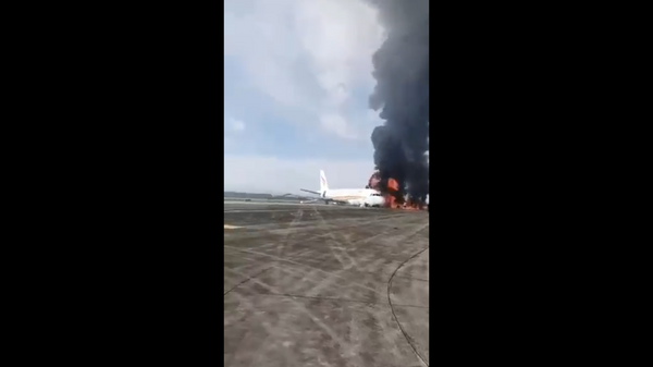 Screenshot captures moment in which the front of a Tibet Airlines plane was engulfed in fire as passengers are seen running to safety.  - Sputnik International