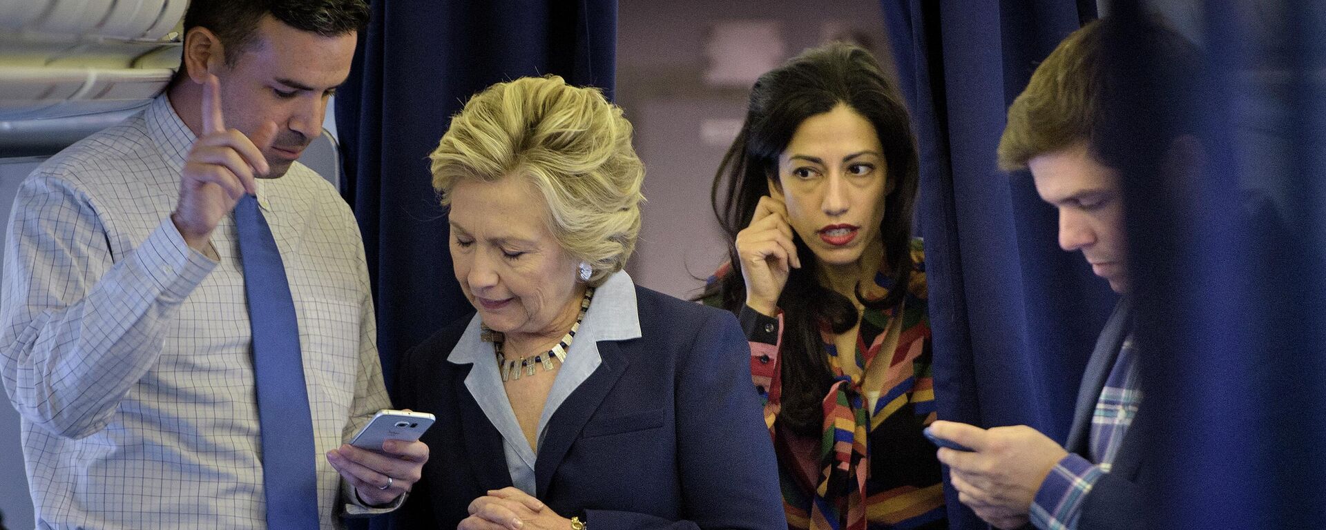 Democratic presidential nominee Hillary Clinton (2L) looks at national press secretary Brian Fallon's (L) smart phone while on her plane with aid Huma Abedin (2R) and traveling press secretary Nick Merrill (R) at Westchester County Airport October 3, 2016 in White Plains, New York - Sputnik International, 1920, 13.05.2022