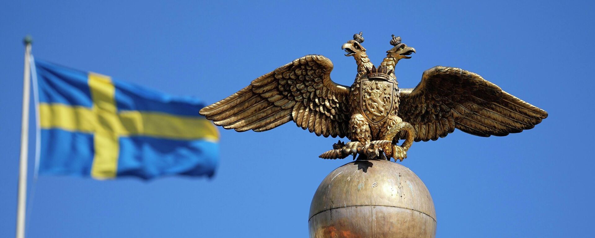 A Russian Imperial double-headed eagle is seen in front of a Sweden flag on the Czarina's Stone in the Market Square, in Helsinki, Finland, Friday, May 13, 2022. - Sputnik International, 1920, 15.05.2022