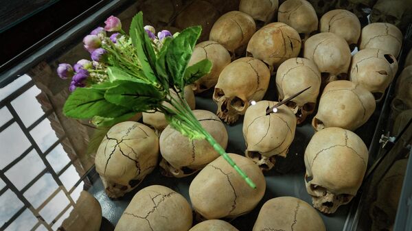 FILE - Flowers are laid on top of a glass case containing the skulls of some of those who were slaughtered as they sought refuge in the church, kept as a memorial to the thousands who were killed in and around the Catholic church during the 1994 genocide, inside the church in Ntarama, Rwanda, on April 5, 2019 - Sputnik International
