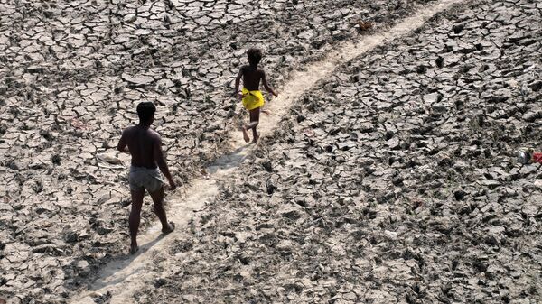 A man and a boy walk across an almost dried up bed of river Yamuna following hot weather in New Delhi, India, Monday, May 2, 2022 - Sputnik International