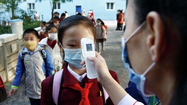 A teacher takes the body temperature of a schoolgirl to help curb the spread of the coronavirus before entering Kim Song Ju Primary School in Central District in Pyongyang, North Korea, Wednesday, Oct. 13, 2021 - Sputnik International