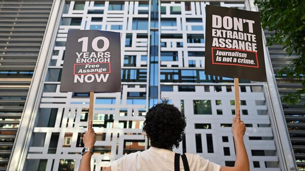 A demonstrator holds two placards while standing in front of Home Office building, in London, on May 17, 2022, to protest against the extradition of Wikileaks founder Julian Assange. - Sputnik International