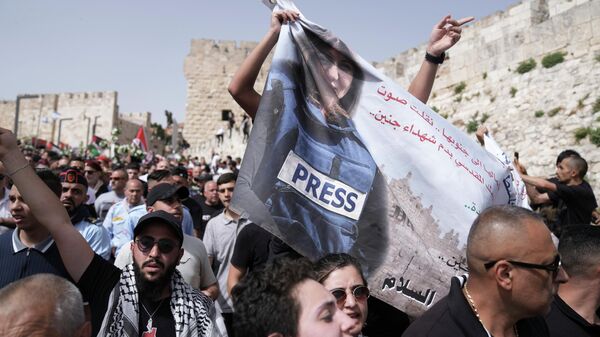Mourners hold a banner depicting slain Al Jazeera veteran journalist Shireen Abu Akleh as they walk from the Old City of Jerusalem to her burial site, Friday, May 13, 2022. - Sputnik International